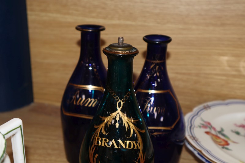 Three Regency gilt decorated blue glass spirit decanters, a Victorian cranberry glass hand bell and claret jug and various ceramics